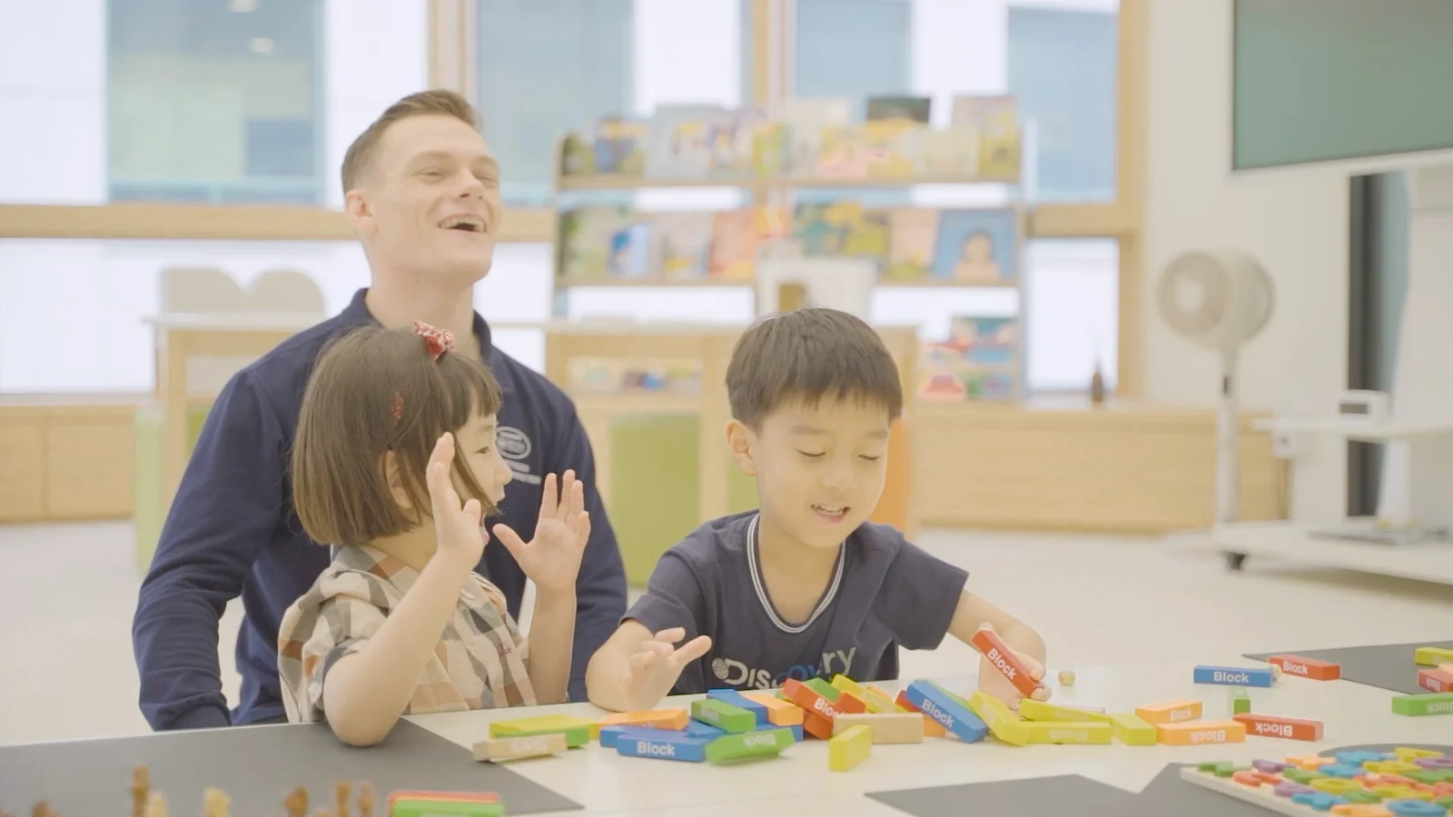 A Crew member kneeling at eye level, laughing with a child during an activity